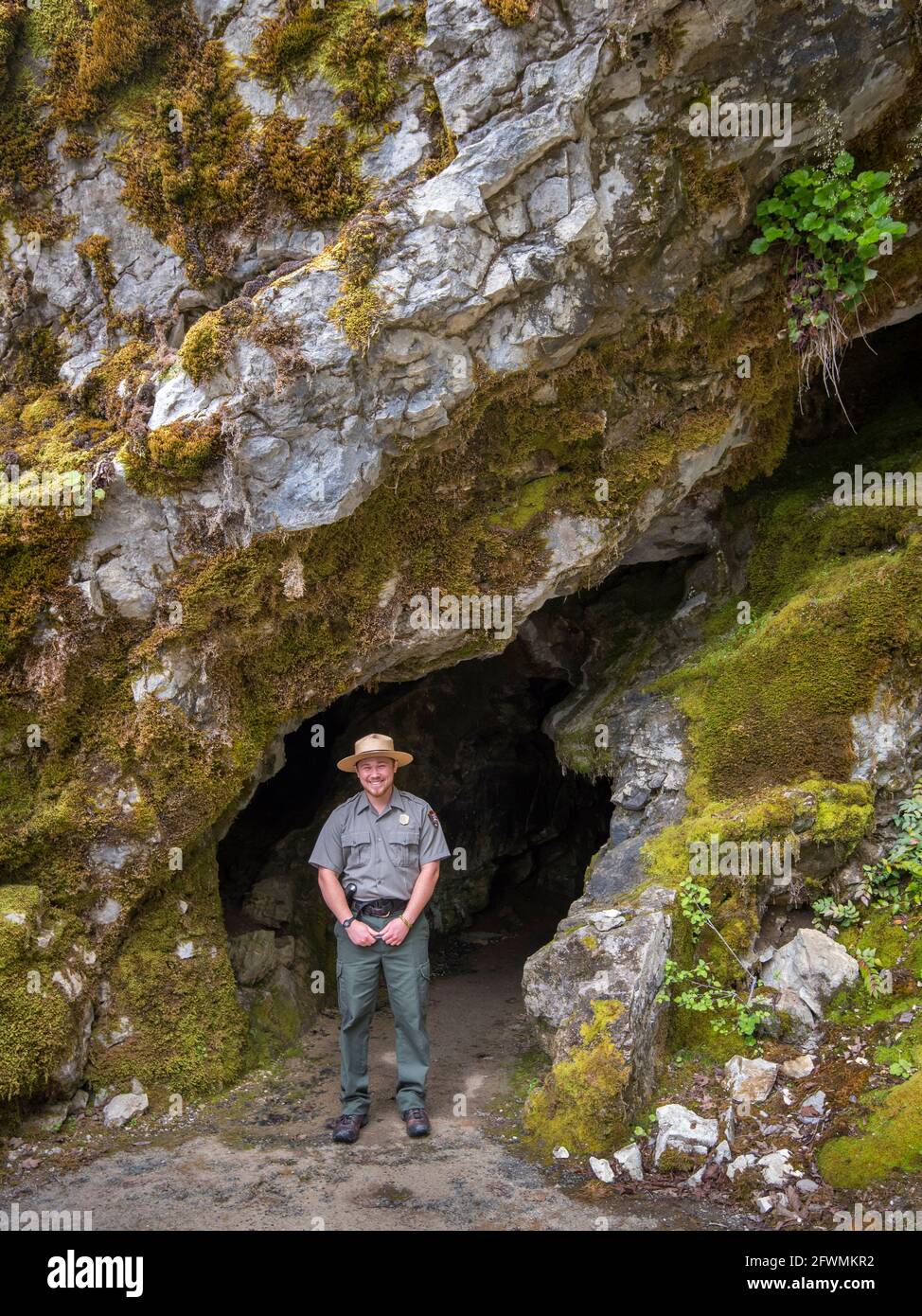 Parque Nacional Ranger Alex Stillson en la entrada de una cueva en el Monumento Nacional de las Cuevas de Oregón, Oregón. Foto de stock