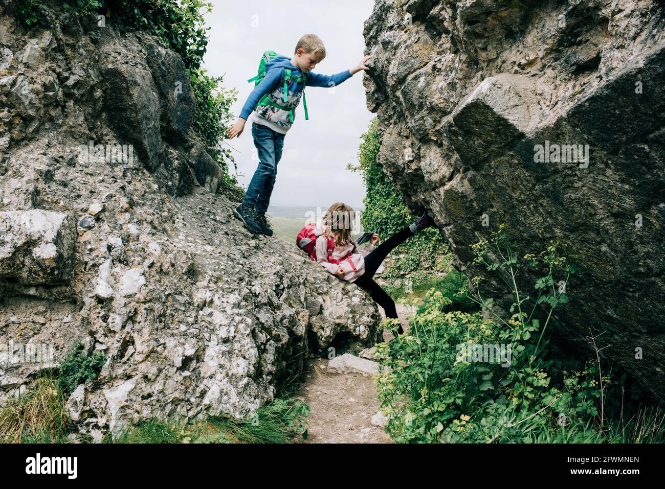 Los niños escalan sobre rocas en el castillo de Corfe explorando el campo Foto de stock