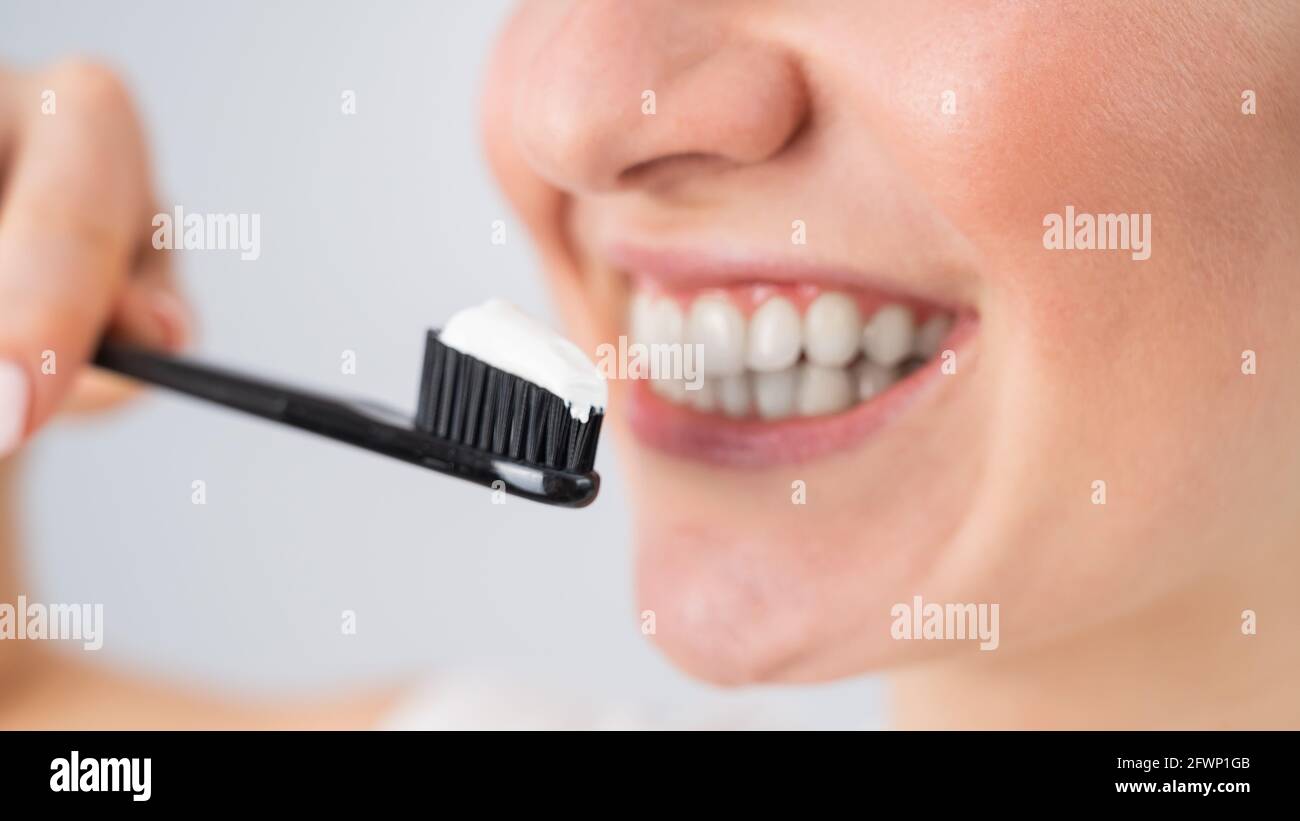 Una mujer con una sonrisa blanca como la nieve sostiene un cepillo de dientes con pegar sobre un fondo blanco Foto de stock
