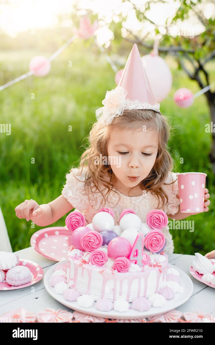 Feliz cumpleaños niña haciendo deseo soplando velas en pastel con  decoración rosa en hermoso jardín. 4 años de cumpleaños. el niño come feliz  cumpleaños rosa cu Fotografía de stock - Alamy