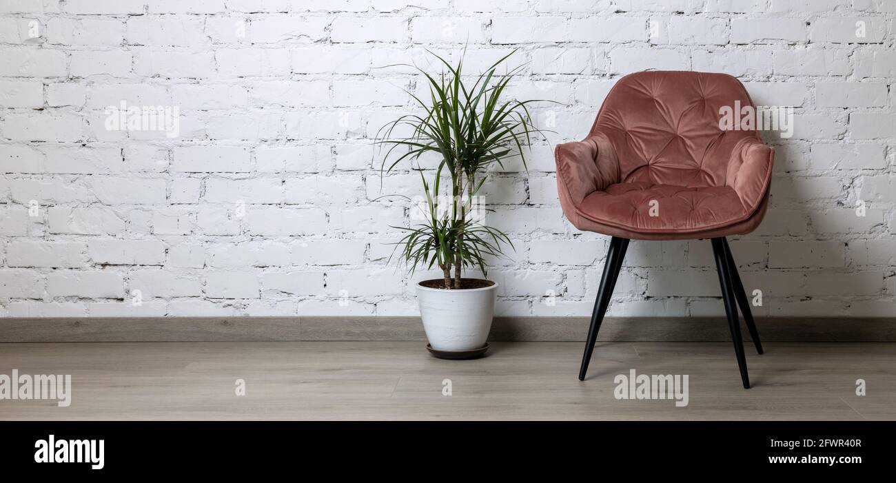 silla rosa y maceta de flores sobre fondo de pared de ladrillo blanco. minimalismo diseño interior. espacio de copia de la bandera Foto de stock