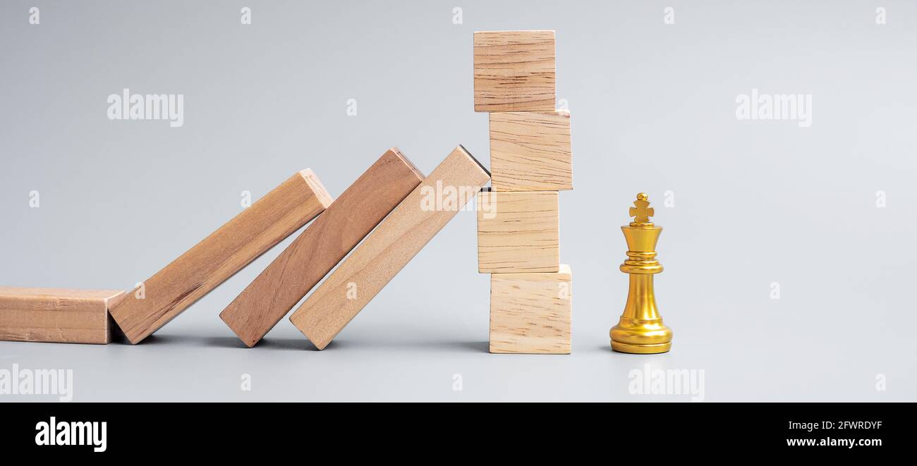 Bloques de madera o dominó cayendo a la figura de rey de ajedrez dorado. Negocio, Gestión de riesgos, Solución, Regresión económica, Seguros Foto de stock