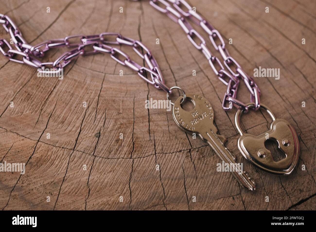 Golpe de cabeza de una llave y una cerradura pequeña con cadenas metálicas  en una superficie de madera Fotografía de stock - Alamy