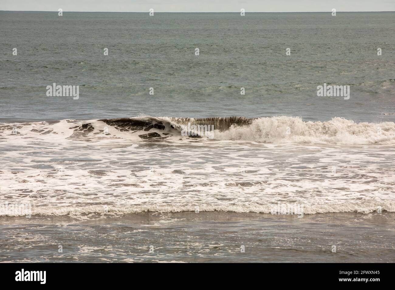 Vista de la playa negra volcánica y de las olas del océano Pacífico en Playa Hermosa en North Puntarenas, Costa Rica Foto de stock