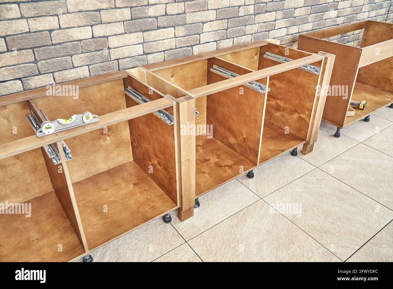 Cajas de madera de muebles de cocina de madera contrachapada y sólida  ceniza de madera instalada de acuerdo al nivel cerca de la pared de  ladrillo cerrar ver Fotografía de stock -
