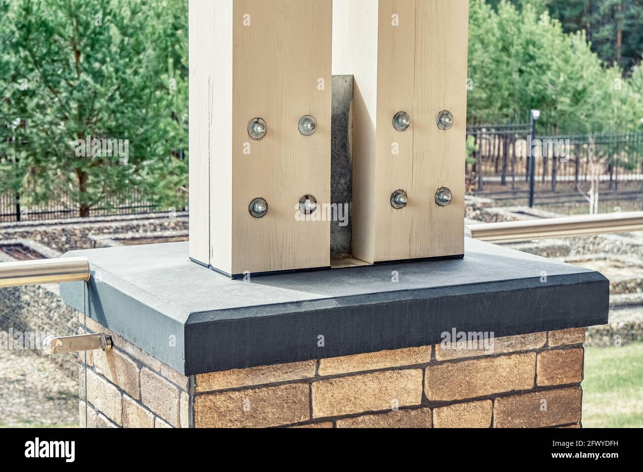 Soporte de postes de madera para techo sobre terraza cimentación de hormigón  decorada con ladrillos contra pinos jóvenes Fotografía de stock - Alamy