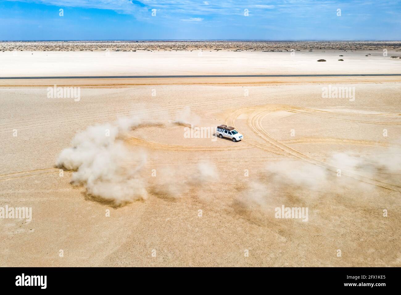 Una vista del paisaje que muestra una duna blanca de un todoterreno que se extiende por el desierto, enviando arena al aire. Namibia, África. Fotografía aérea de aviones teledirigidos Foto de stock