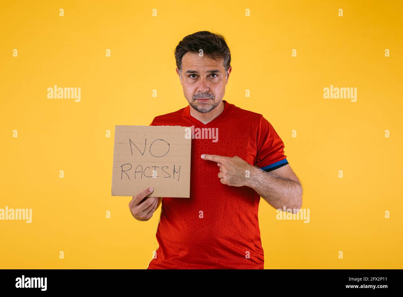 Fan de fútbol con camiseta roja y un signo que dice 'No hay racismo' Foto de stock