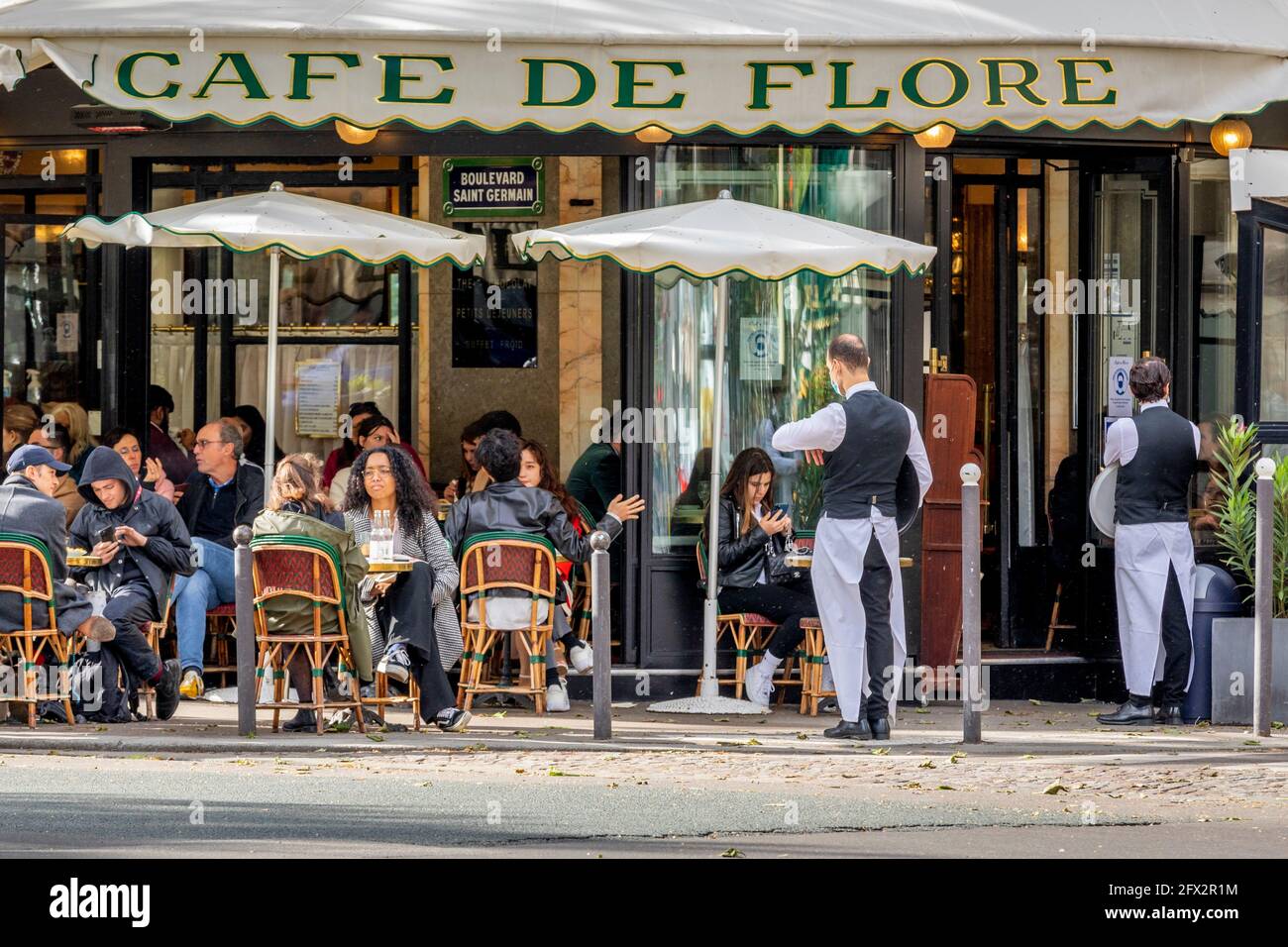 París, Francia - 19 de mayo de 2021: Día después del cierre debido al covid-19 en un famoso café parisino. 2 camareros llevan máscaras quirúrgicas Foto de stock