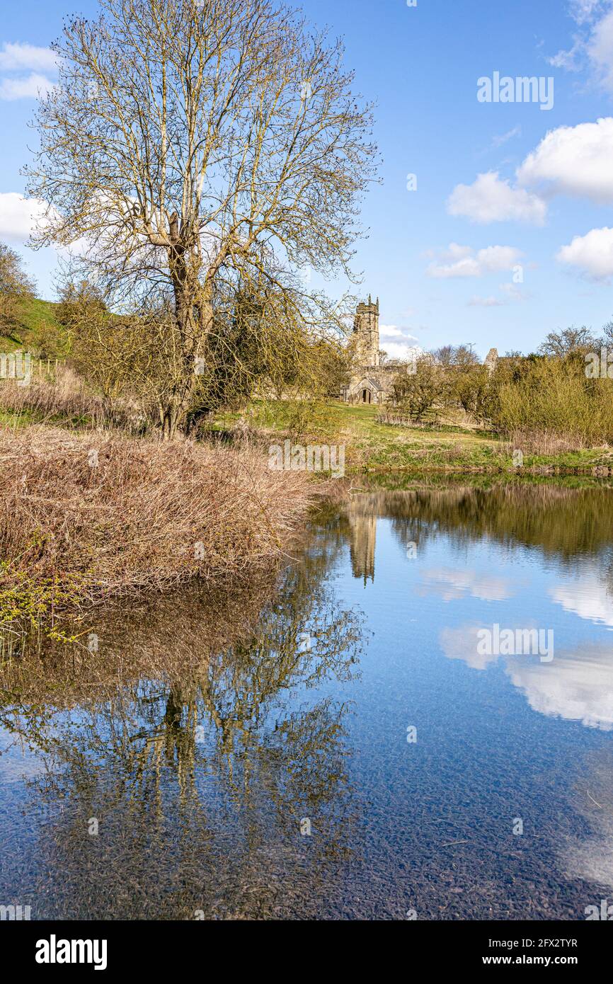 Las ruinas de la iglesia de San Martins se reflejaron en un estanque de molino abandonado en Wharram Percy desierta villa medieval en los Yorkshire Wolds, North Yorkshire, Foto de stock