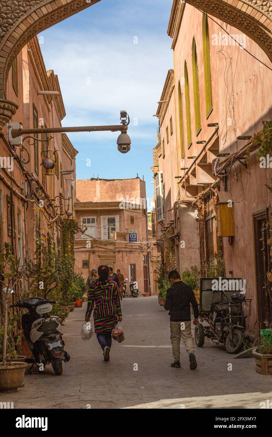 Vista trasera de un par de personas caminando en una calle brillante de Kashgar. República Popular de China Foto de stock