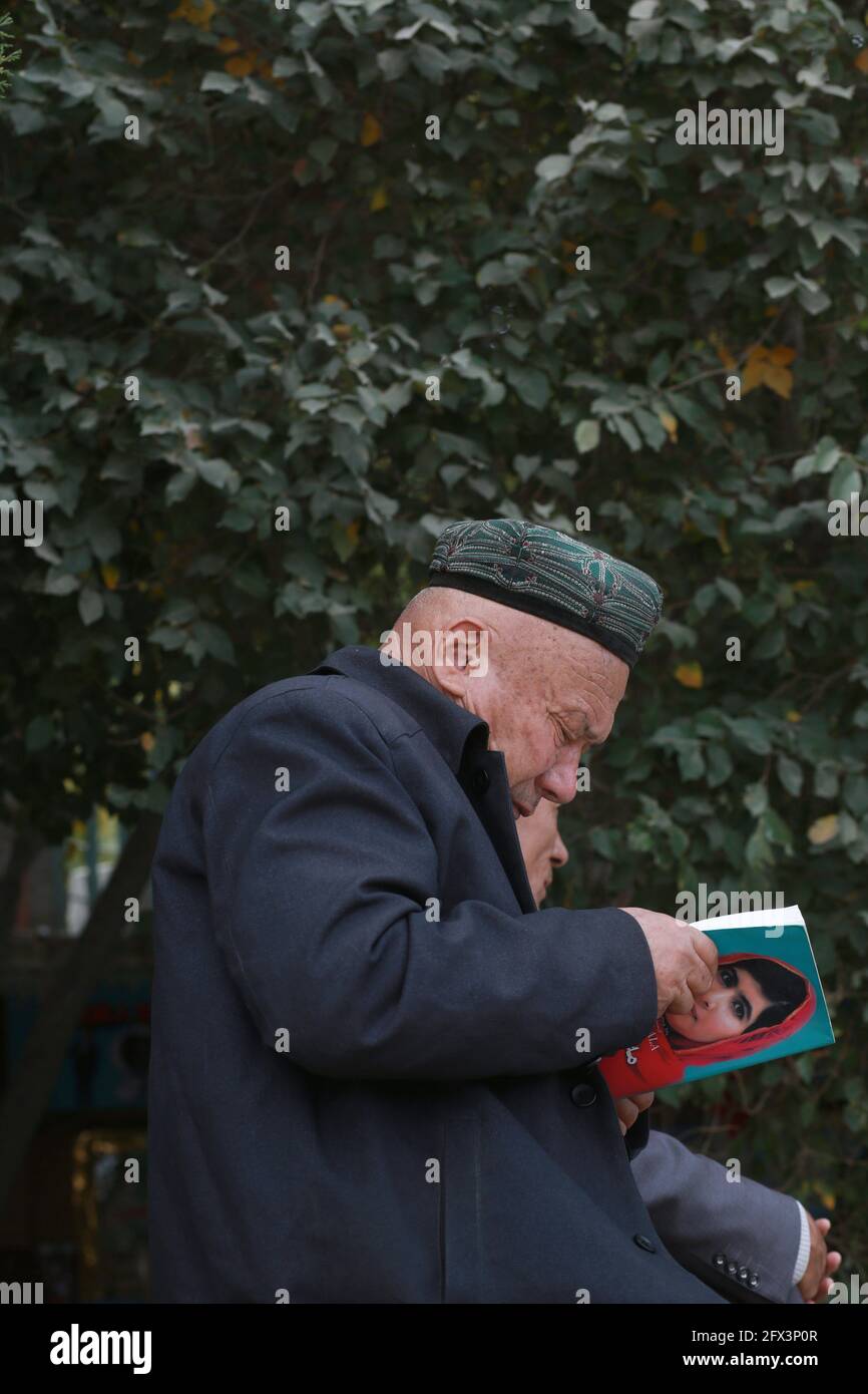 Uighur anciano leyendo fuera de la Mezquita de Id Kah .Kashgar, Xingiang, China 2019 Foto de stock