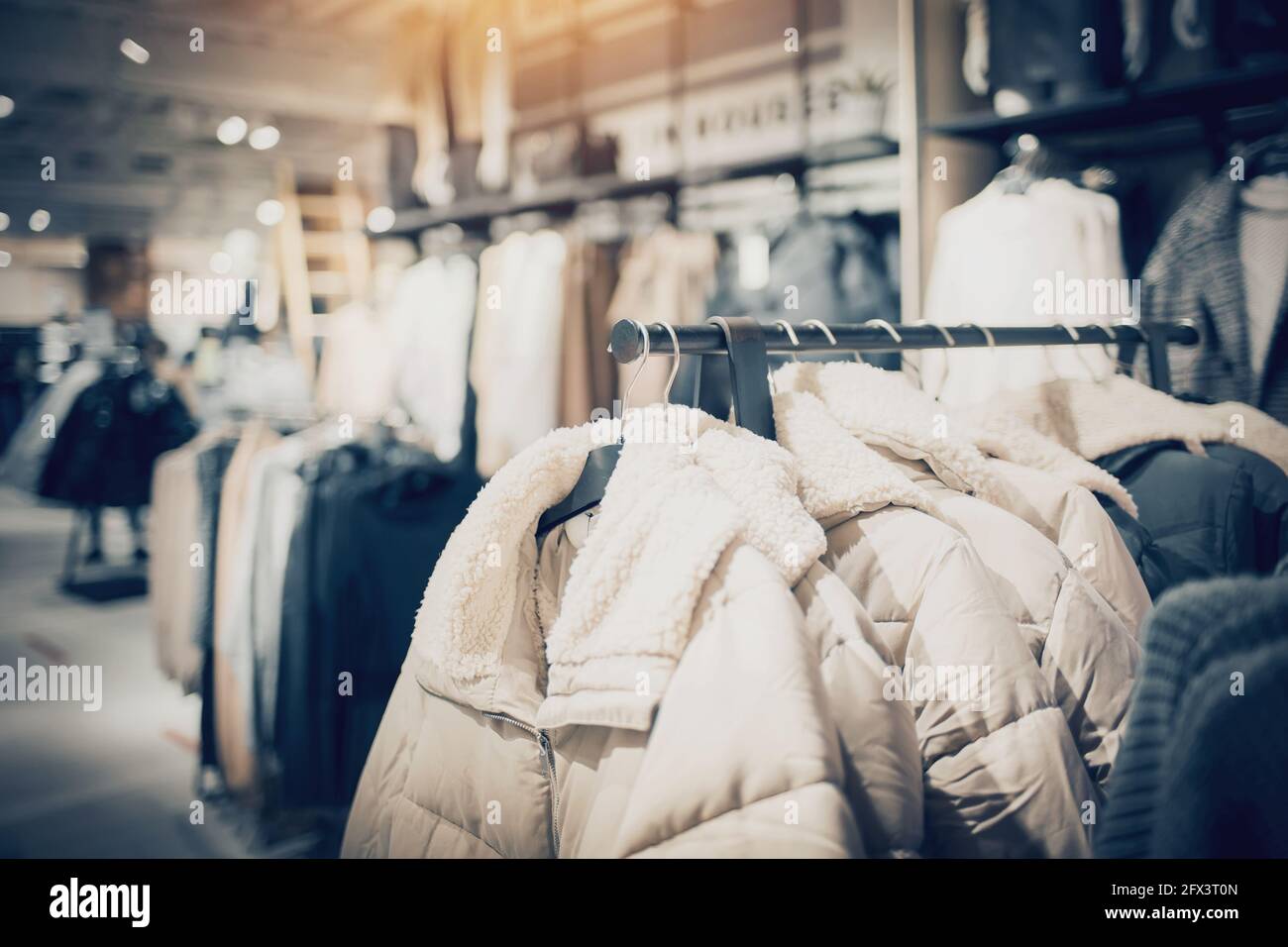 Compras en la tienda. Ropa en perchas en la tienda para la venta. Desenfoque el fondo. Ropa de en una boutique. Varias prendas de vestir en el mercado Fotografía de stock -