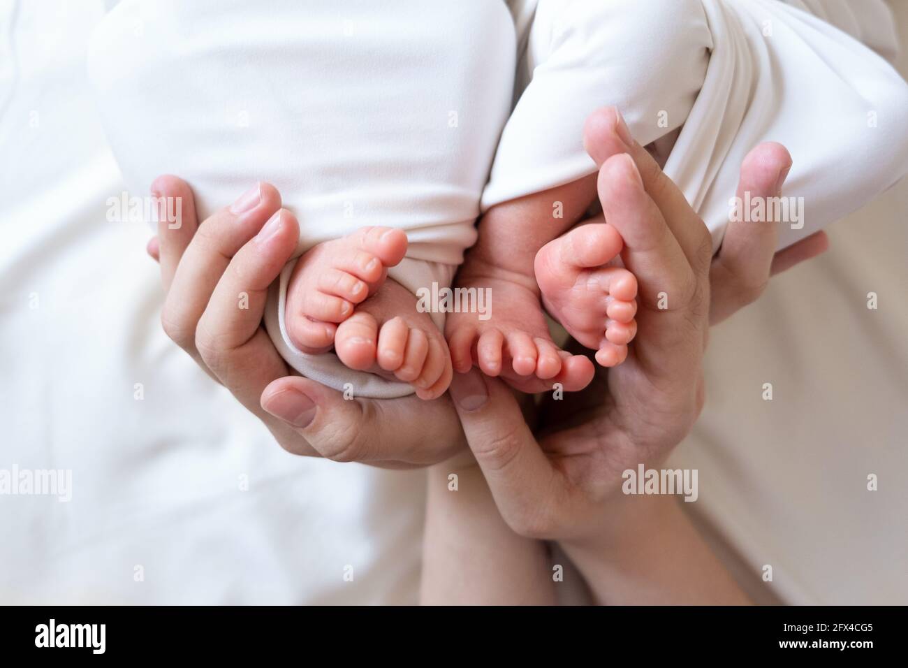 Las Manos De Mama Y Papa Sostienen Las Piernas Pequenas De Sus Dos Bebes Recien Nacidos Gemelos Fotografia De Stock Alamy