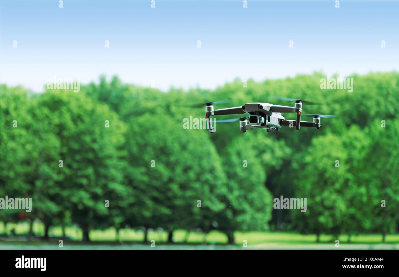 quadcopter con cámara fotográfica profesional volando sobre árboles verdes del parque antecedentes Foto de stock
