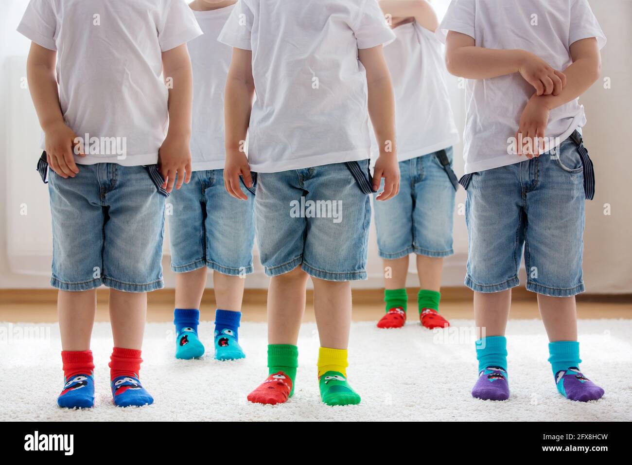 Pies para niños con diferentes calcetines en fila, los niños usan diferentes calcetines coloridos Fotografía de stock -