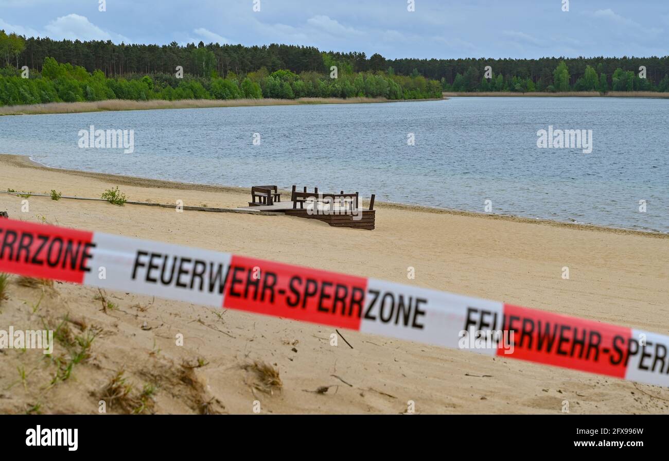 26 de mayo de 2021, Brandeburgo, Frankfurt (Oder): Un acceso a la playa del Helenesee se cordonó con una cinta de aleteo. Partes del lago Helene cerca de Frankfurt (Oder) ya no son accesibles para los visitantes debido al riesgo de toboganes. La Oficina Estatal de Minería, Geología y Materias Primas (LBGR) ha cerrado toda la costa norte y oeste como medida de precaución. En marzo, se había producido un corrimiento de tierras, y el LBGR había examinado el área geotécnicamente. Según la evaluación, no se pudieron descartar más deslizamientos de tierra, se dijo ahora. Las zonas costeras afectadas por el cierre se van a ampliar g Foto de stock
