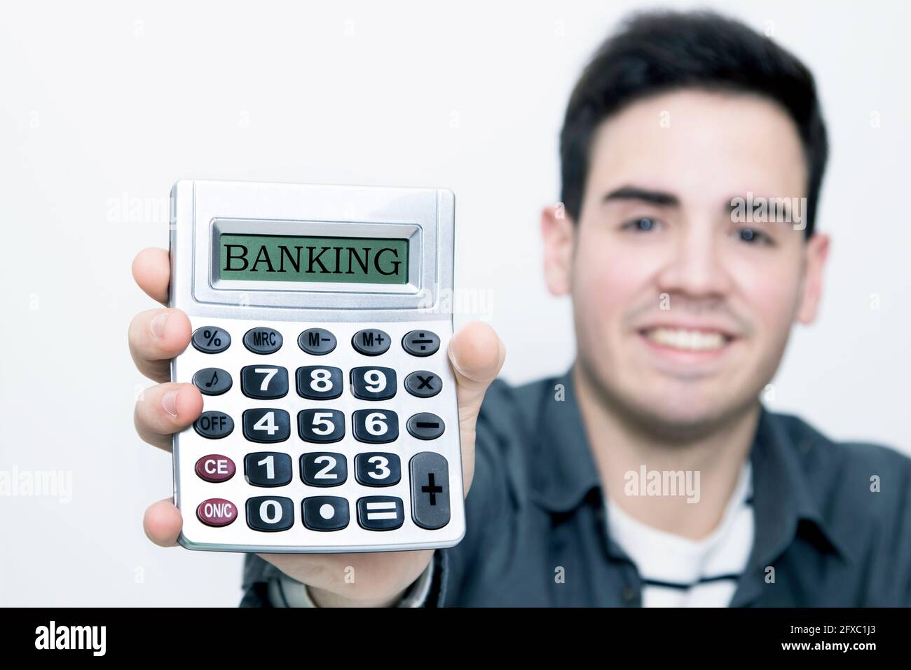 calculadora en primer plano con el hombre al fondo sonriendo Foto de stock