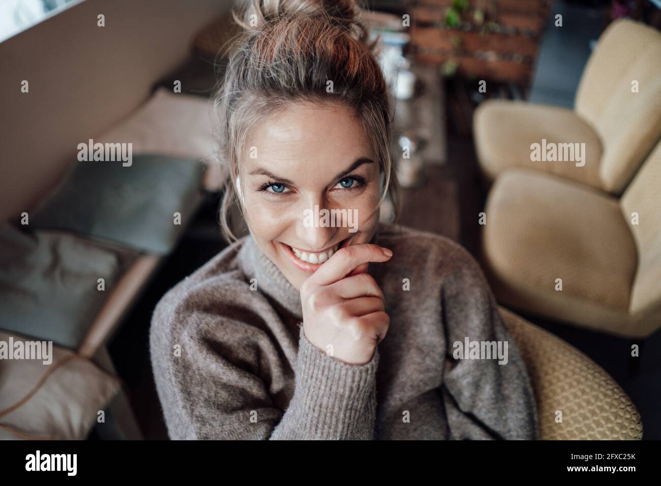 Una mujer hermosa sonriente con la mano en el mentón en el café Foto de stock