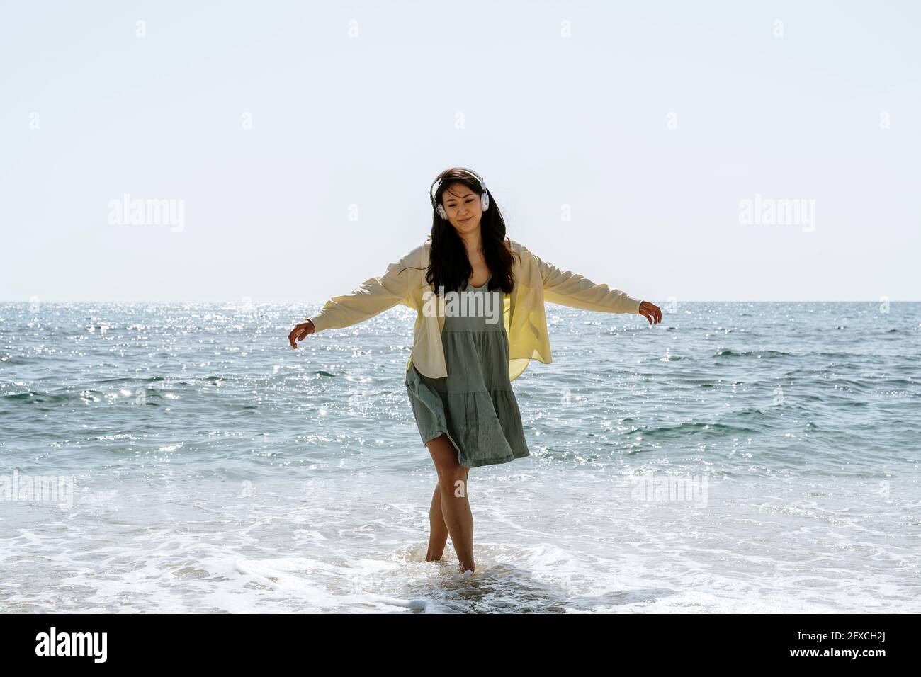 Mujer con los brazos extendidos de pie en el agua durante el día soleado Foto de stock