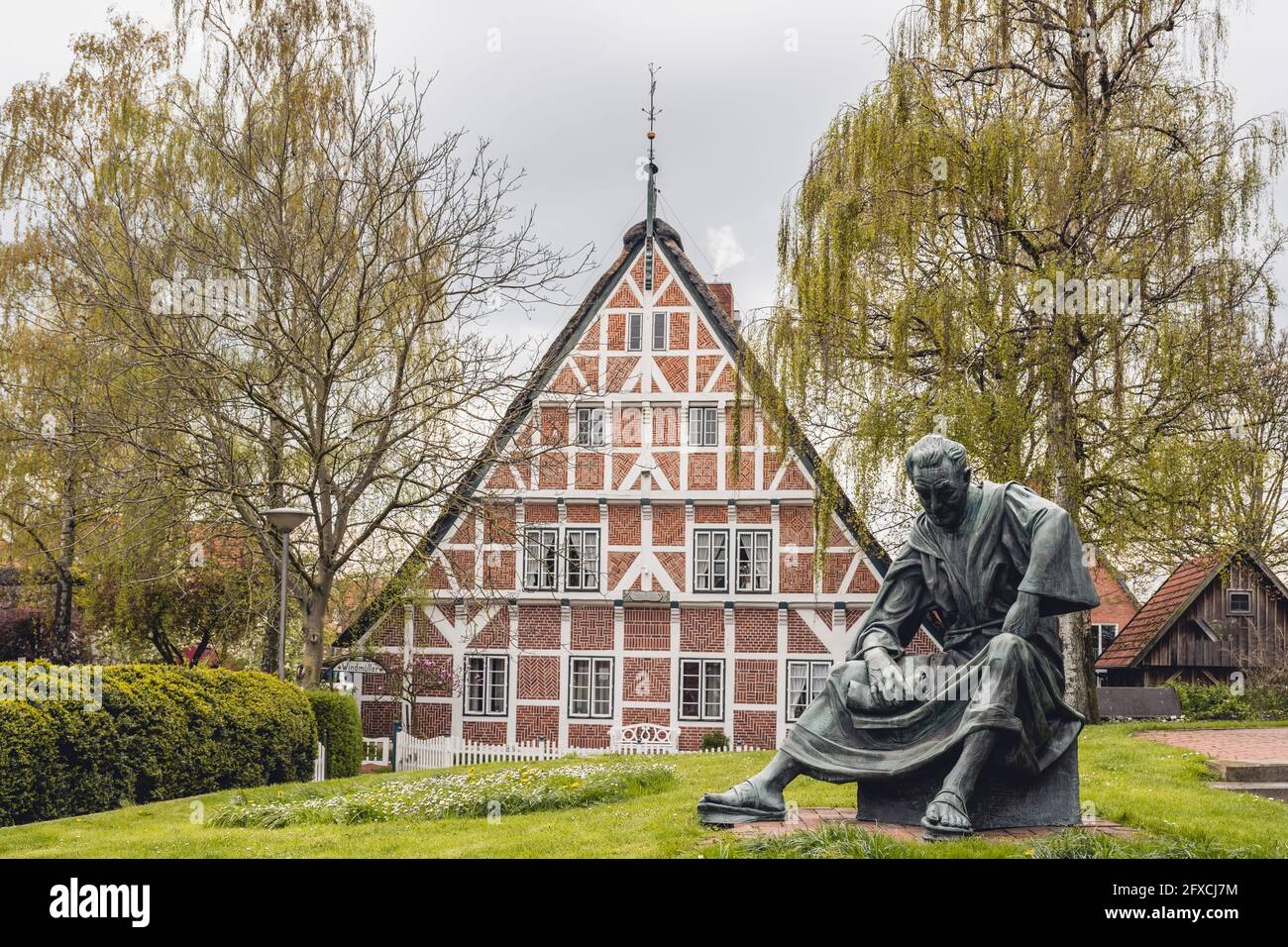 Alemania, Altes Land, casa de entramado de madera con estatua del sacerdote Heinrich von Carsten Eggers en primer plano Foto de stock