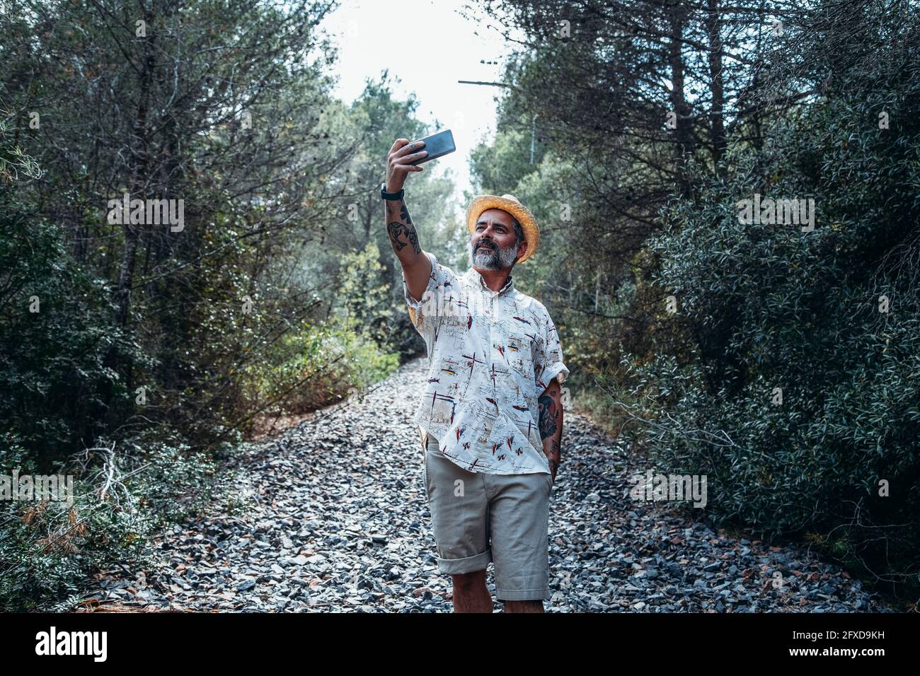 Hombre barbudo haciendo una selfie en la pista de tren abandonada en la montaña Foto de stock