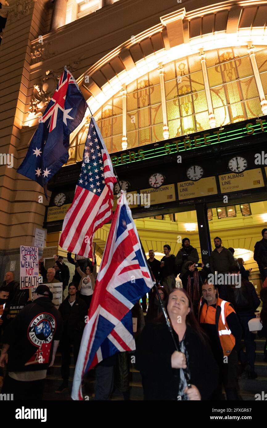 Melbourne, Australia 27 de mayo de 2021, un manifestante lleva 3 banderas durante una rápida manifestación de manifestantes antiencerrados fuera de la estación Flinders Street de Melbourne, donde los manifestantes expresan sus opiniones sobre el cierre de 7 días que comenzará a medianoche de esta noche. Crédito: Michael Currie/Alamy Live News Foto de stock