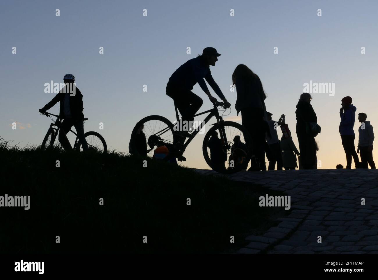 Sillhouettes de caminantes y ciclistas pasan su tiempo después del trabajo o de ocio en una montaña urbana. Aislado en el fondo. Foto de stock