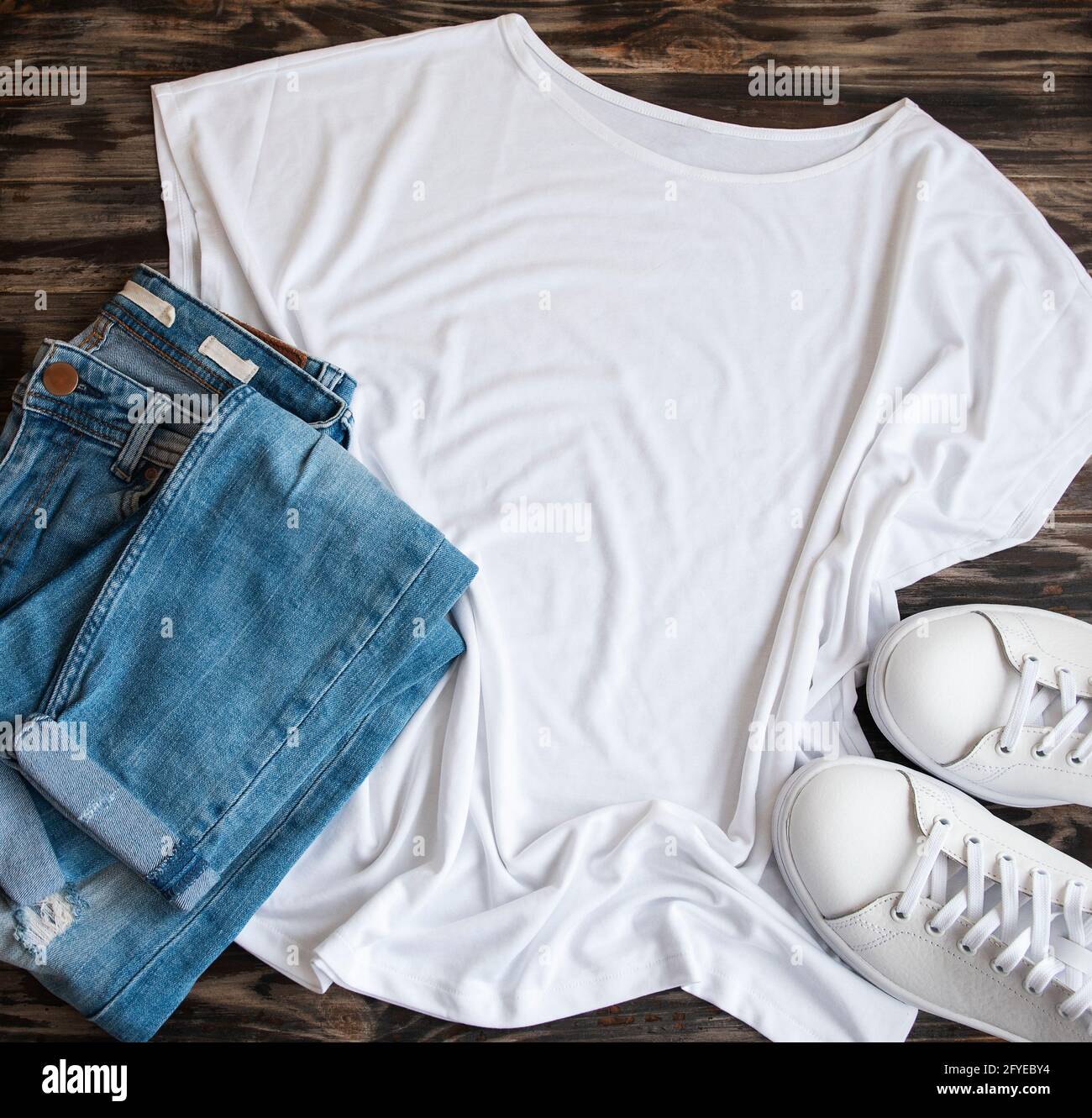 Elegante conjunto de ropa para mujer. Traje de mujer sobre fondo de madera.  Camiseta blanca, sneakers blancas y gafas de sol. Plano, vista superior  Fotografía de stock - Alamy