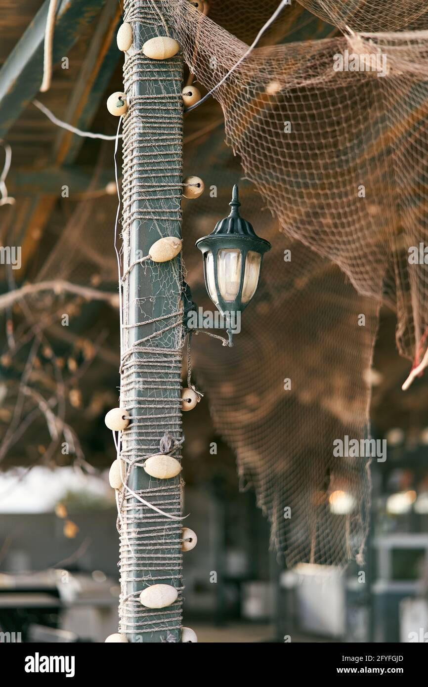 La linterna cuelga de una columna trenzada con aparejos de pesca debajo un  dosel con una red de pesca Fotografía de stock - Alamy