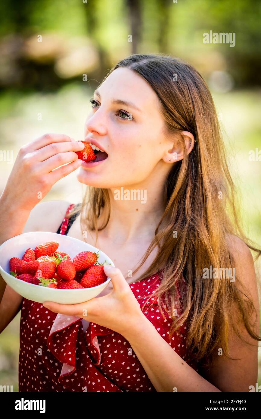 Mujer joven comer fresas. Foto de stock