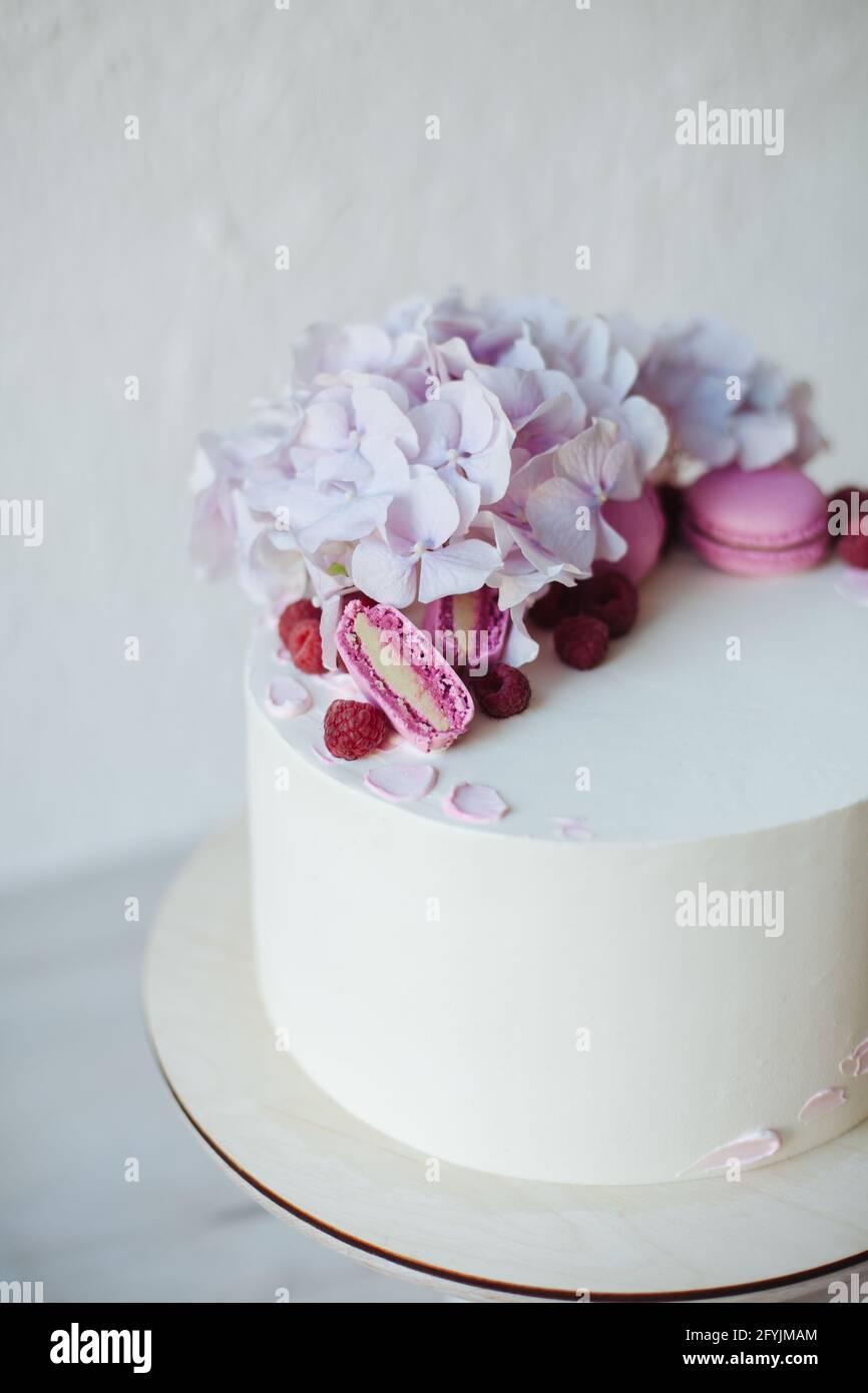 Primer plano de un bizcocho de crema de mantequilla decorado con macarrones rosados y flores de hortensias Foto de stock