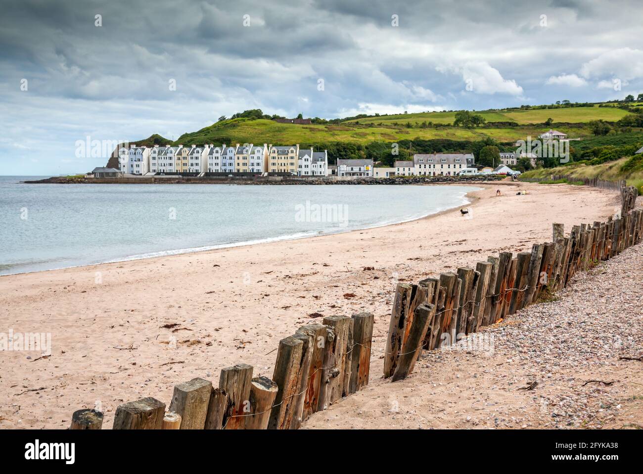 La playa y el rompeolas de madera en el pintoresco pueblo de Cushendun en la costa del condado de Antrim, Irlanda del Norte. Foto de stock