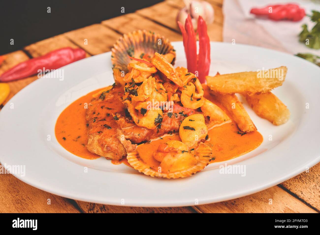 Comida PERUANA: Plato Peruano A lo macho fish, mesa de madera, servido en  un plato blanco, (pescado frito en salsa de mariscos, acompañado por bream  de mar de patata a Fotografía de