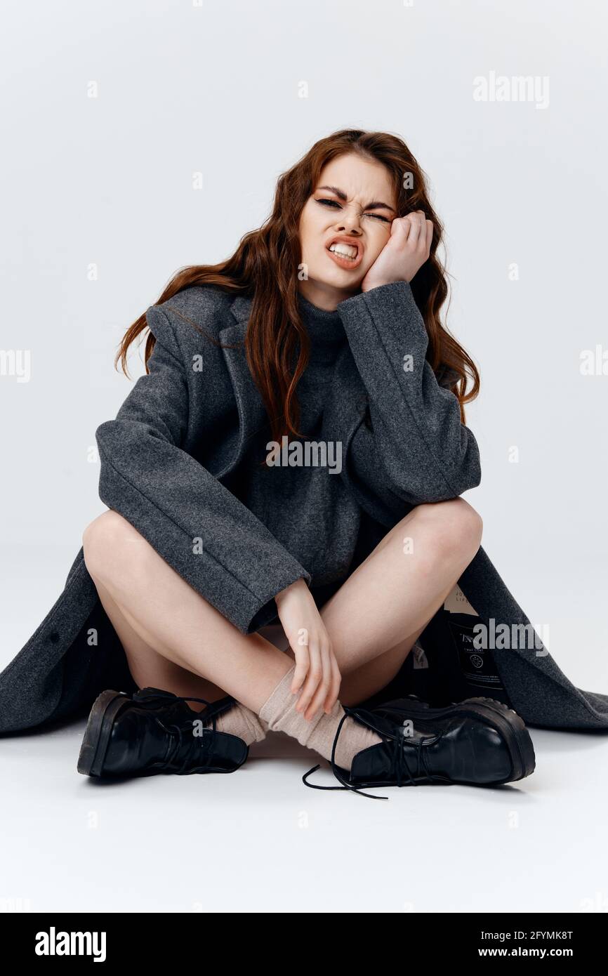 mujer sentada en el suelo con las piernas cruzadas y abrigo botas cara  triste Fotografía de stock - Alamy