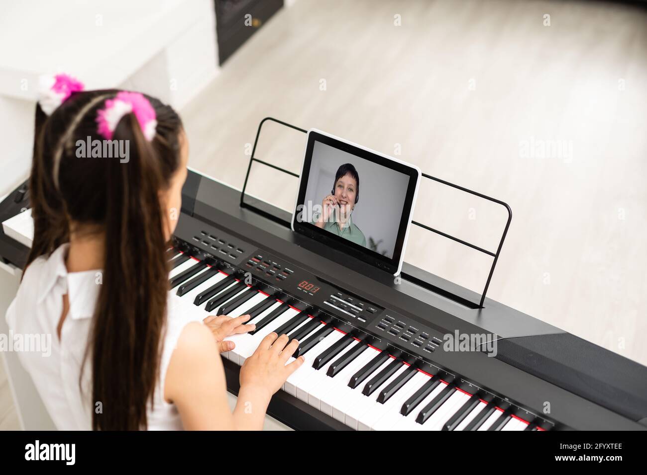 la niña toca el piano en la educación en clase con la tableta en home online  learning in covid-19 crisis quarantine Fotografía de stock - Alamy