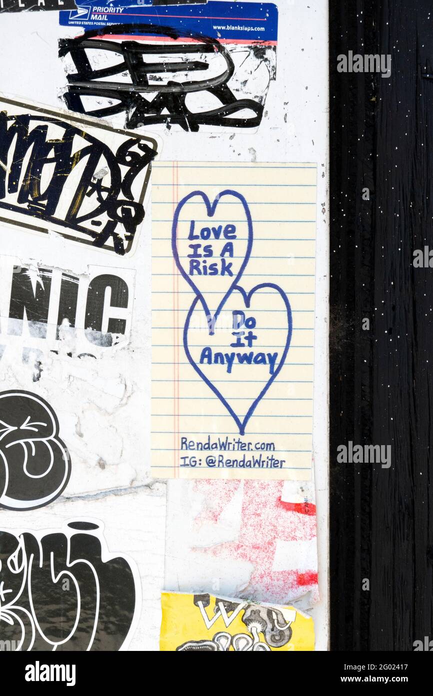 Un collage de etiquetas, pegatinas, graffiti y un mensaje sobre el amor. En un puesto de puerta en la calle Steinway en Astoria, Queens, Nueva York. Foto de stock