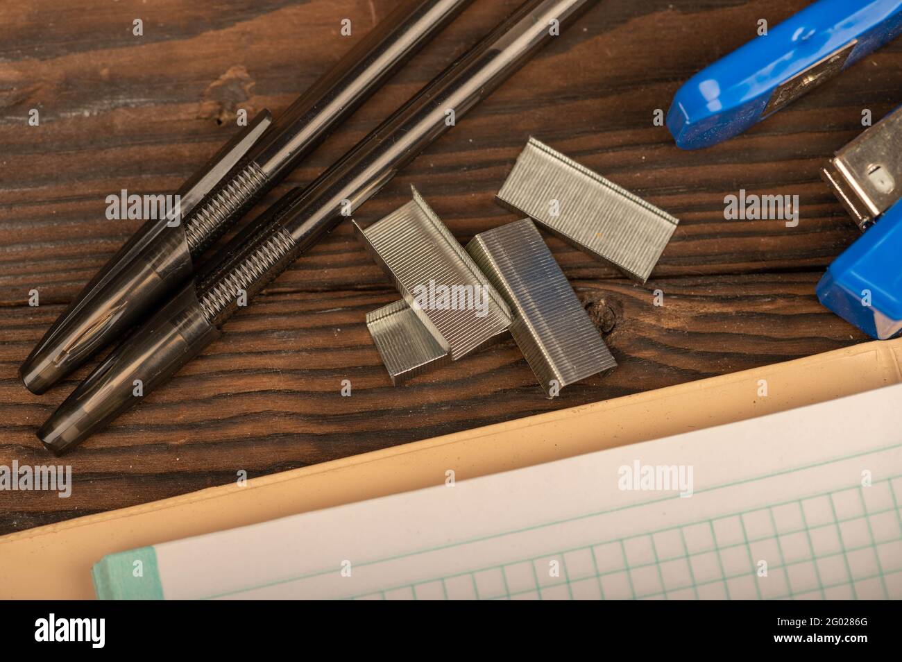 bolígrafo, grapadora y la grapadora grapan una hoja de cuaderno a cuadros en una mesa de madera. Primer plano, enfoque selectivo. Auto-desarrollo durante el Fotografía de - Alamy