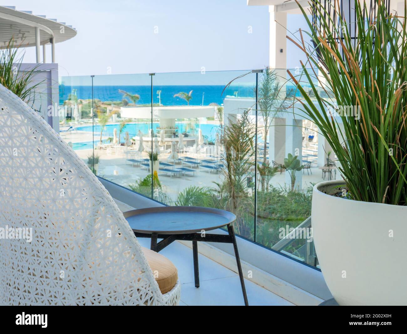 Silla blanca de wicket vacía, mesa baja y planta grande en una terraza con  vista a la piscina y al mar mediterráneo en Napa, Chipre. Hotel solitario  Fotografía de stock - Alamy