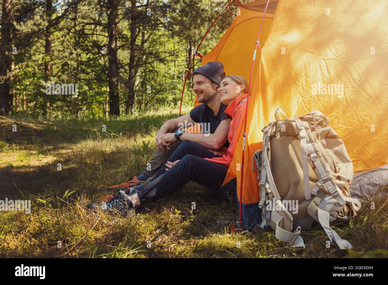 viaje de camping - pareja joven sentada en tienda de campaña en el camping y relajarse después de la caminata Foto de stock