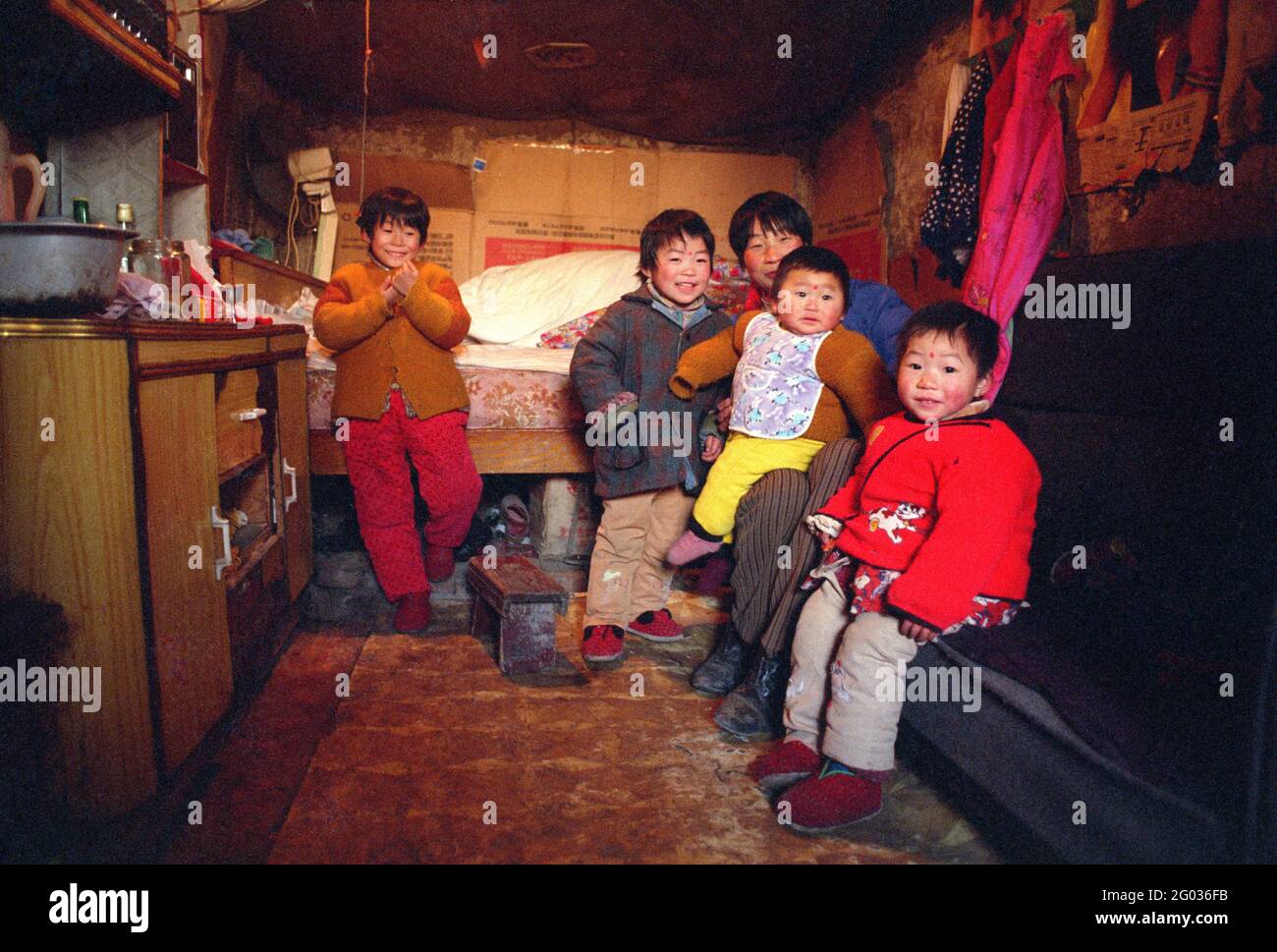 Una madre de la provincia de Henan y cuatro de sus cinco hijos se encuentran en su casa en Beijing, China, en 1998. El niño más joven en sus brazos es el único niño. Foto de stock