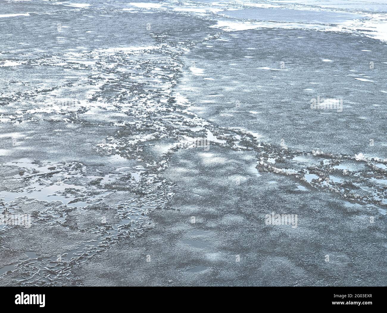 Hielo roto de color azul oscuro en el río. Trozos de hielo picado sobre agua oscura. Resumen de fondo de hielo. Fondo azul con grietas en la surfa de hielo Foto de stock