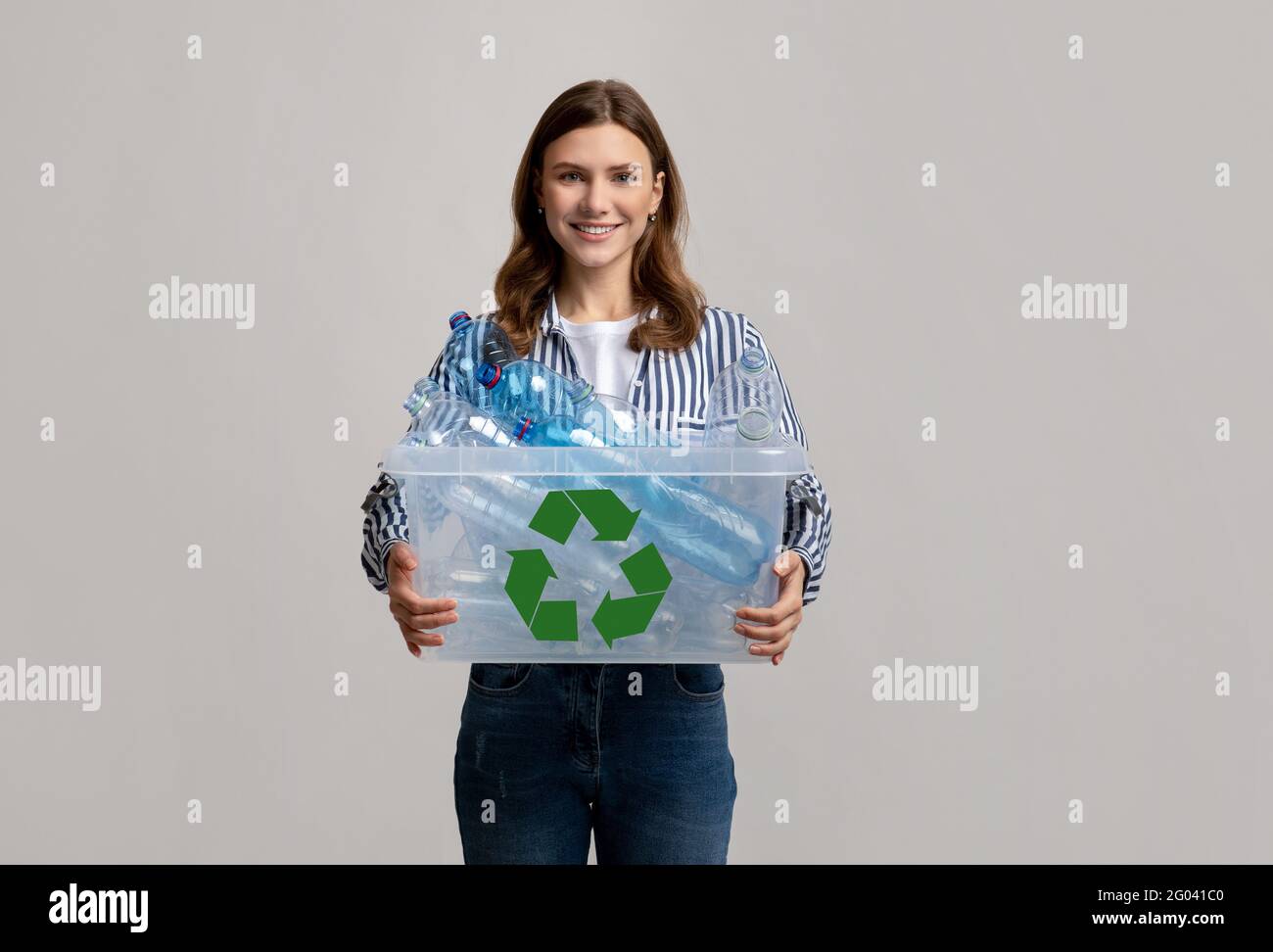 Reutilización de residuos. Alegre Mujer Joven Contenedor de transporte con botellas de plástico para el reciclaje Foto de stock