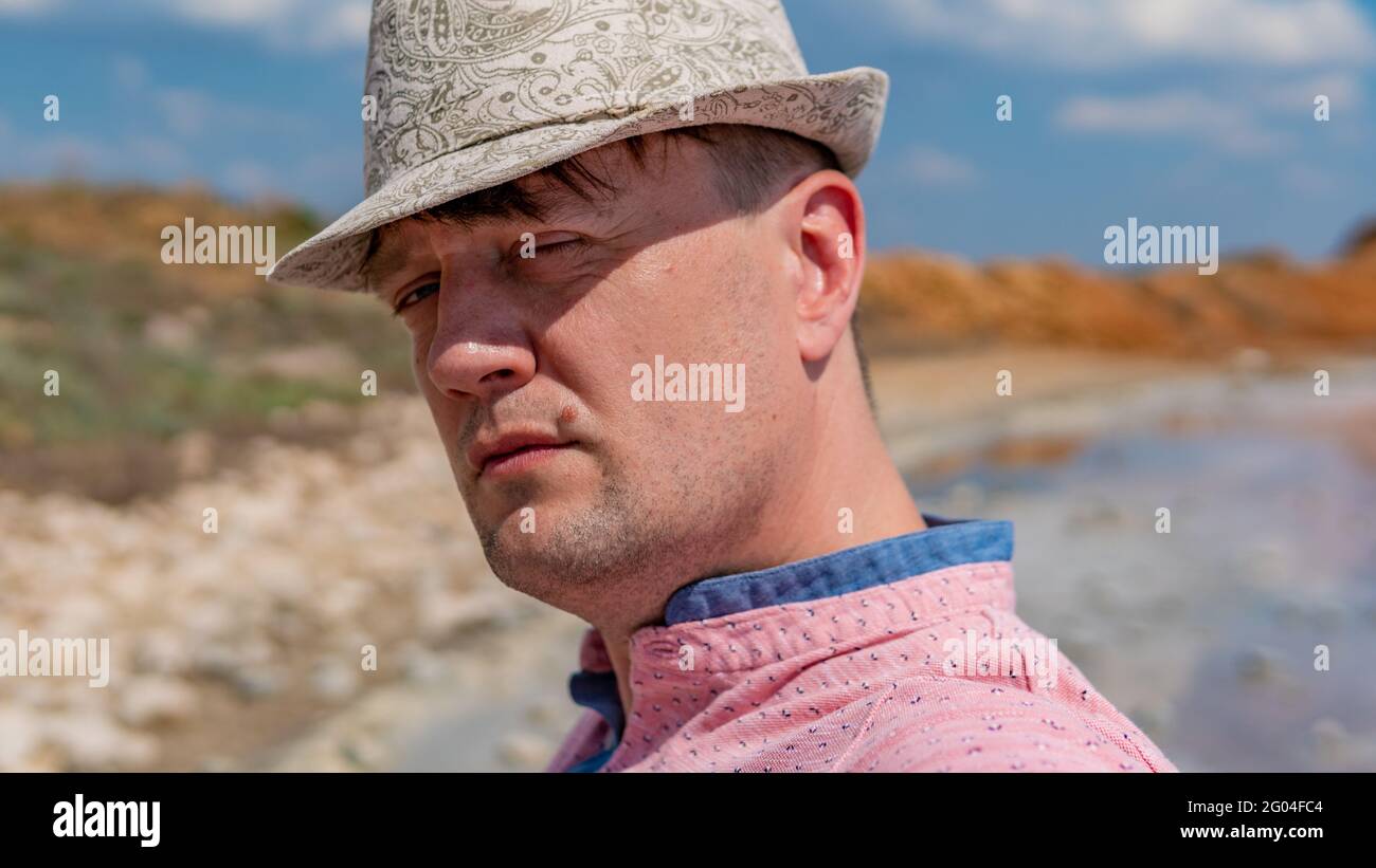 Retrato joven serio usando un sombrero con aspecto caucásico ojos azules brillantes de la luz del día Foto de stock