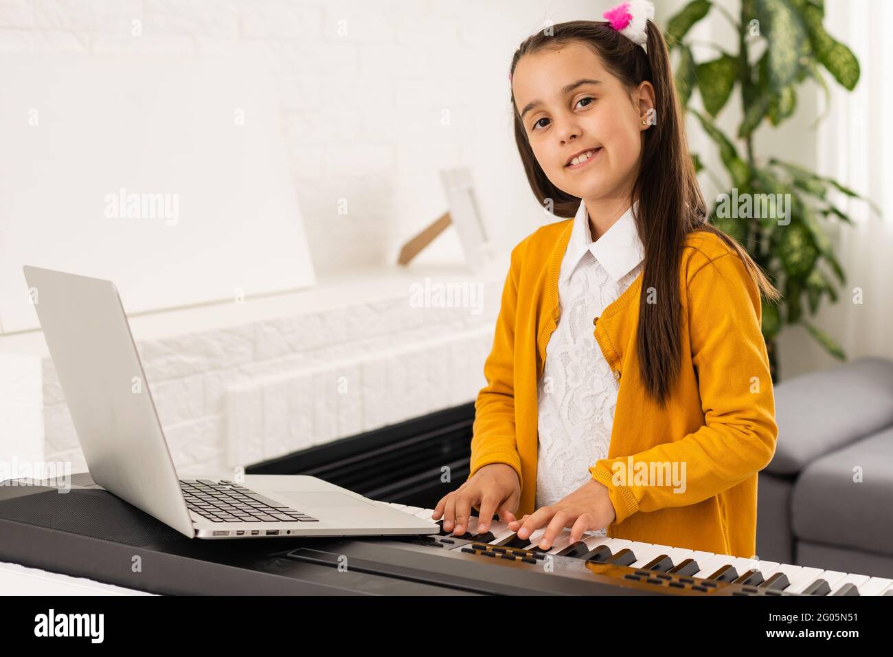la niña toca el piano en la clase con el portátil home ...