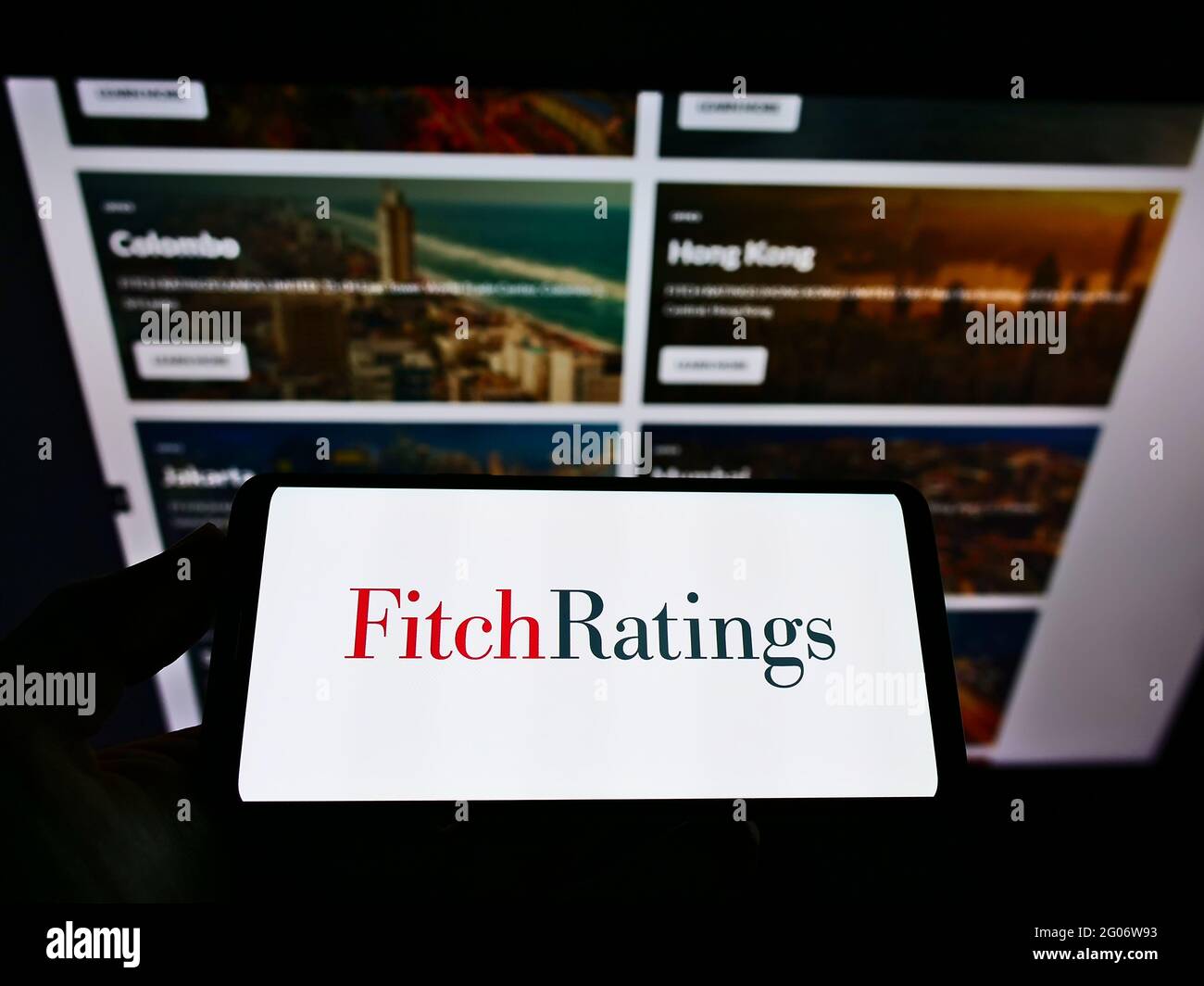 Persona que sostiene el smartphone con el logotipo de la agencia de calificación crediticia estadounidense Fitch Ratings Inc. En la pantalla frente al sitio web. Enfoque en la pantalla del teléfono. Foto de stock