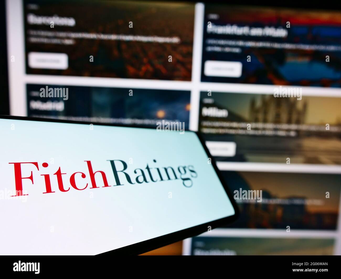 Teléfono móvil con el logotipo de la agencia estadounidense de calificación de crédito Fitch Ratings Inc. En la pantalla frente al sitio web de la empresa. Enfoque en la parte central izquierda de la pantalla del teléfono. Foto de stock