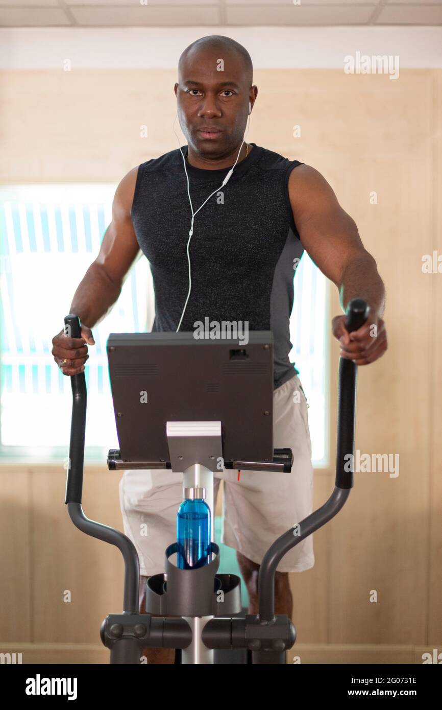 Deportista masculino negro haciendo ejercicios cardiovasculares en el gimnasio. Foto de stock