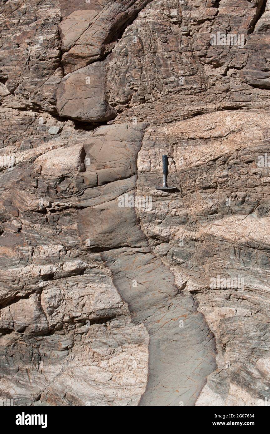 Dique basáltico con márgenes refrigerados que invaden la roca metamórfica (gneiss) y compensada por una pequeña falla, el sudeste de California. Martillo de roca para balanza. Foto de stock