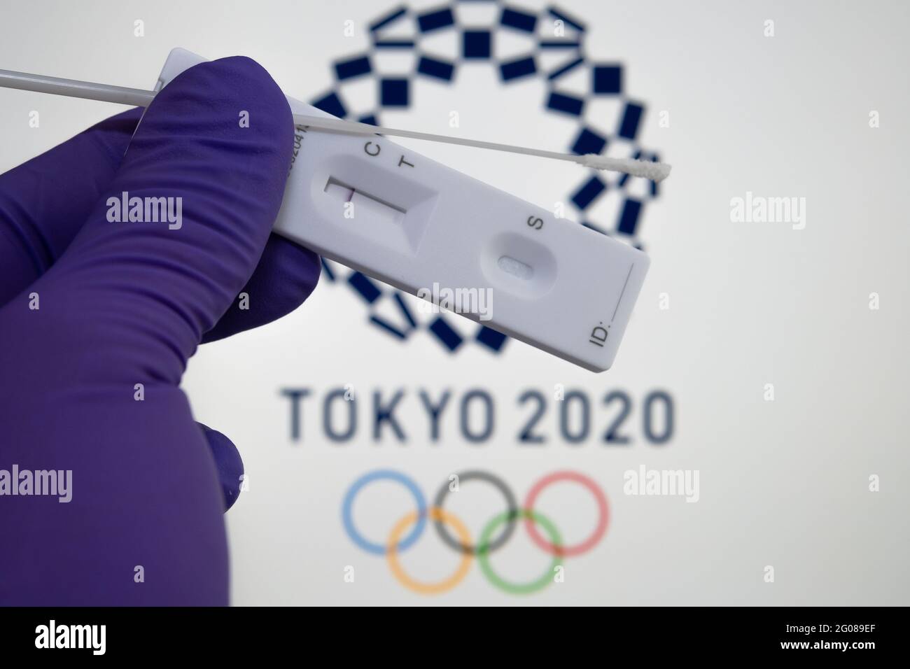 Prueba de PCR negativa en la parte frontal y logotipo de Tokyo 2020 borroso en el fondo borroso. Concepto para los Juegos Olímpicos COVID de Tokio en 2021. Stafford, Rey Unido Foto de stock